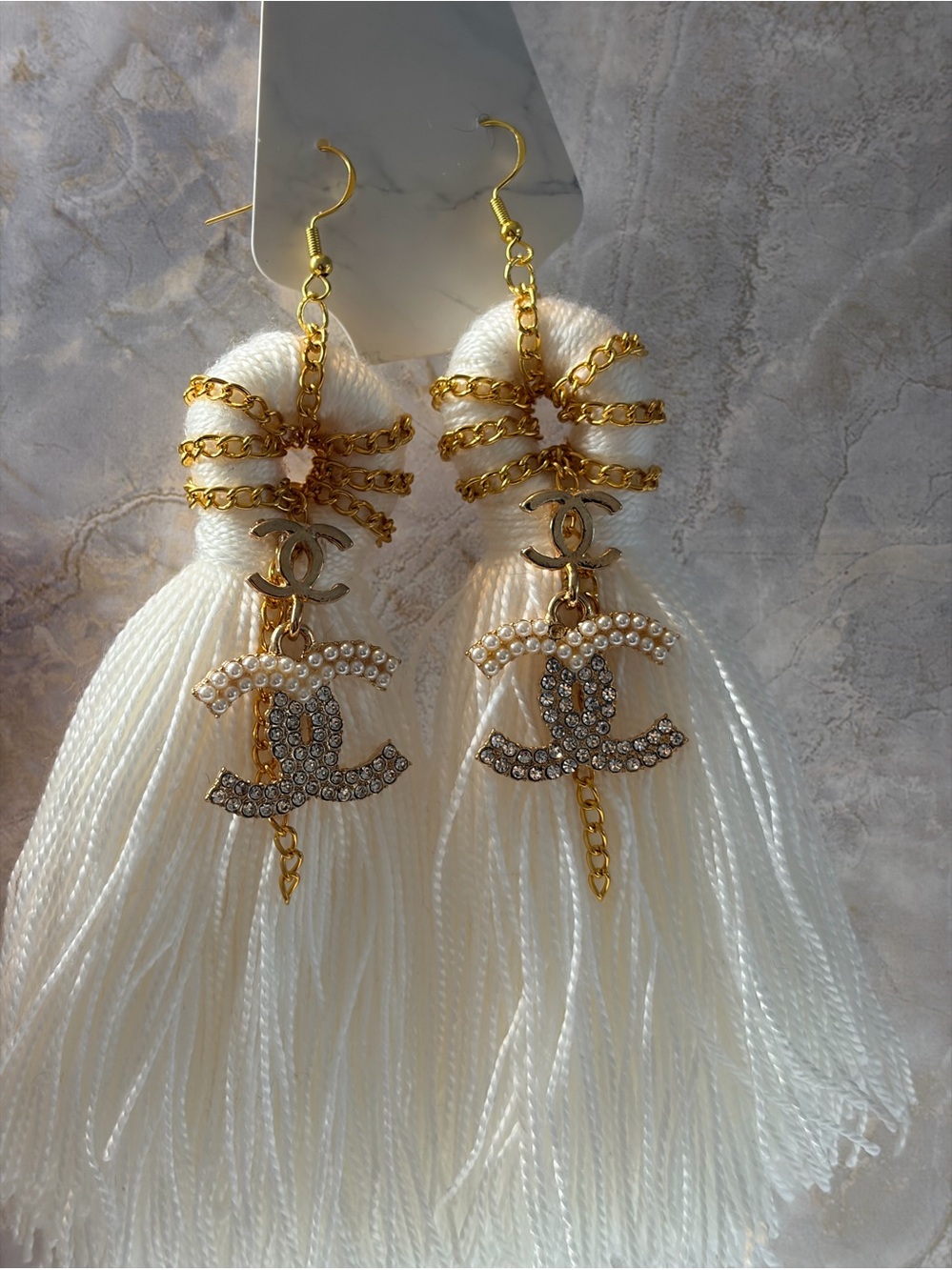 Elegant White Tassel Earrings with Gold and Crystal Logo Accent